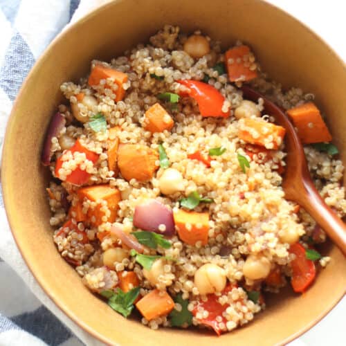 Quinoa and roasted vegetables combined in a bowl with dressing.