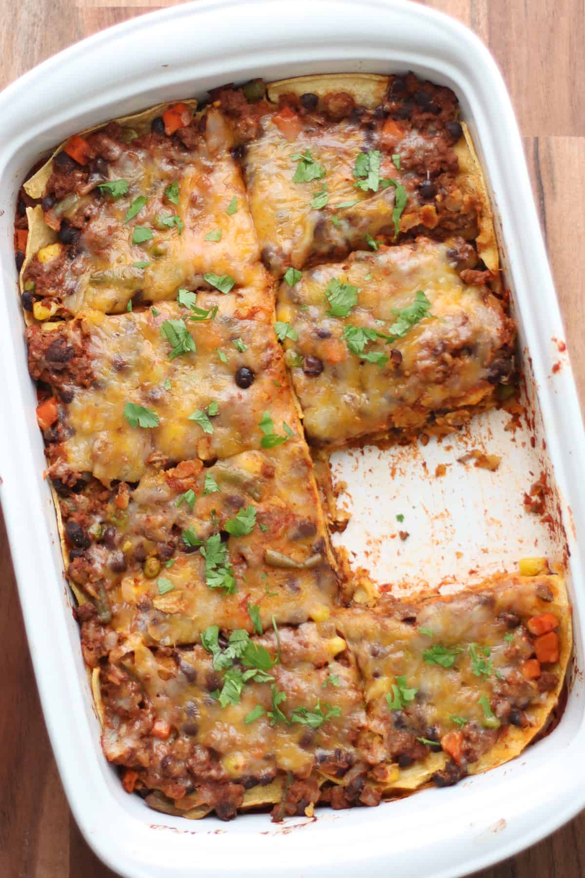 An overhead shot of baked enchilada casserole with a slice taken out.