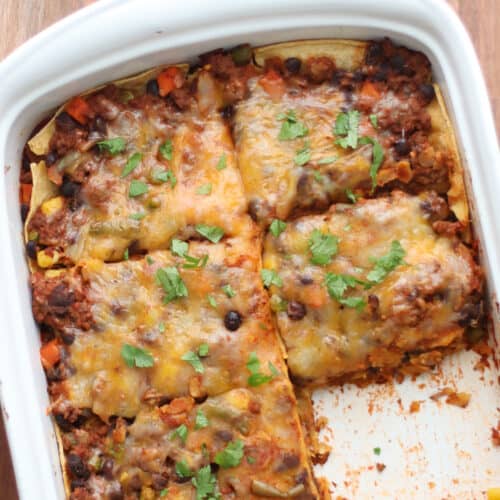 An overhead shot of baked enchilada casserole with a slice taken out.