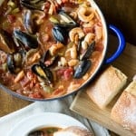 A big pot of seafood coping with a side of bread
