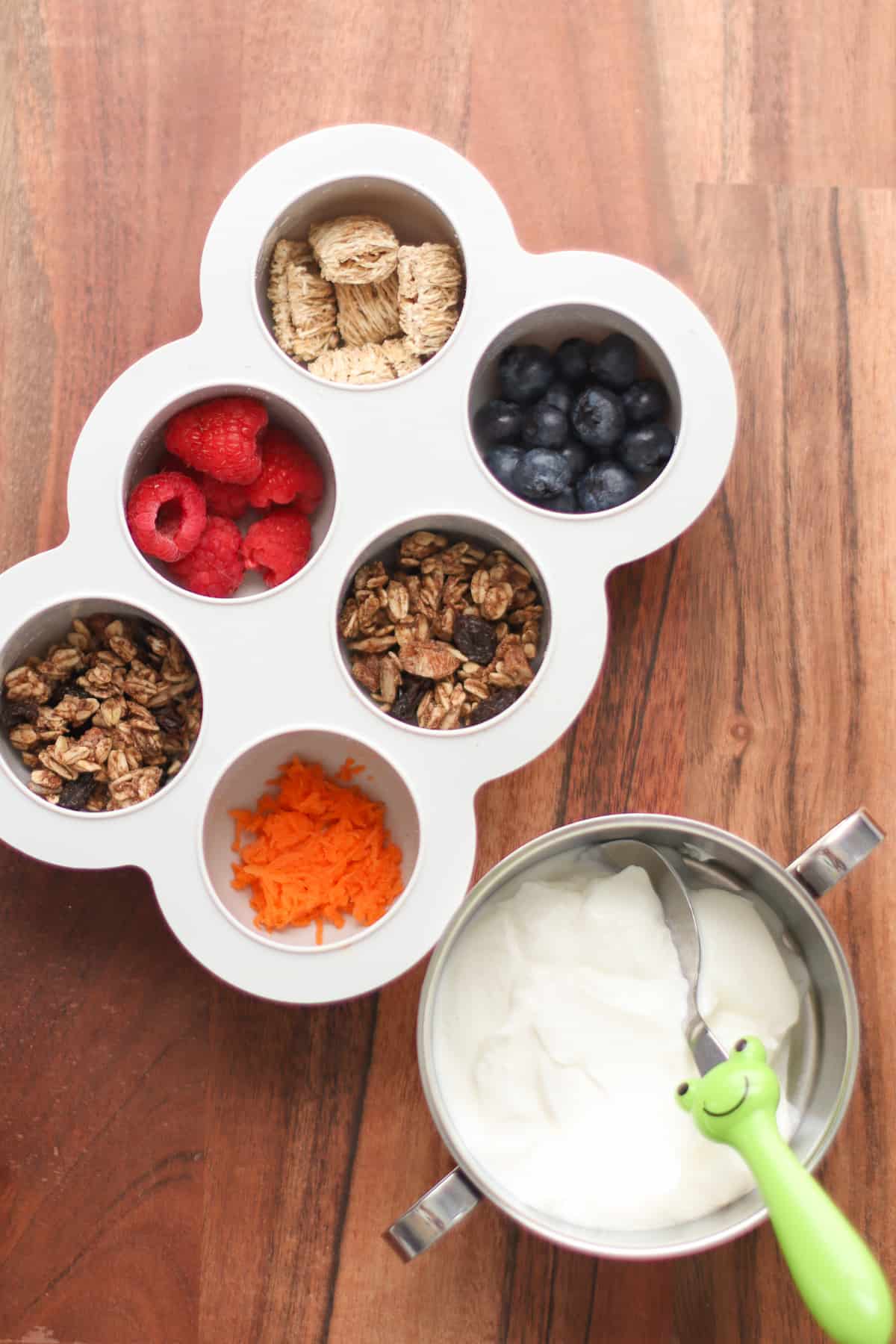 Favorite yogurt toppings in a 6 cup muffin tray with yogurt on the side.