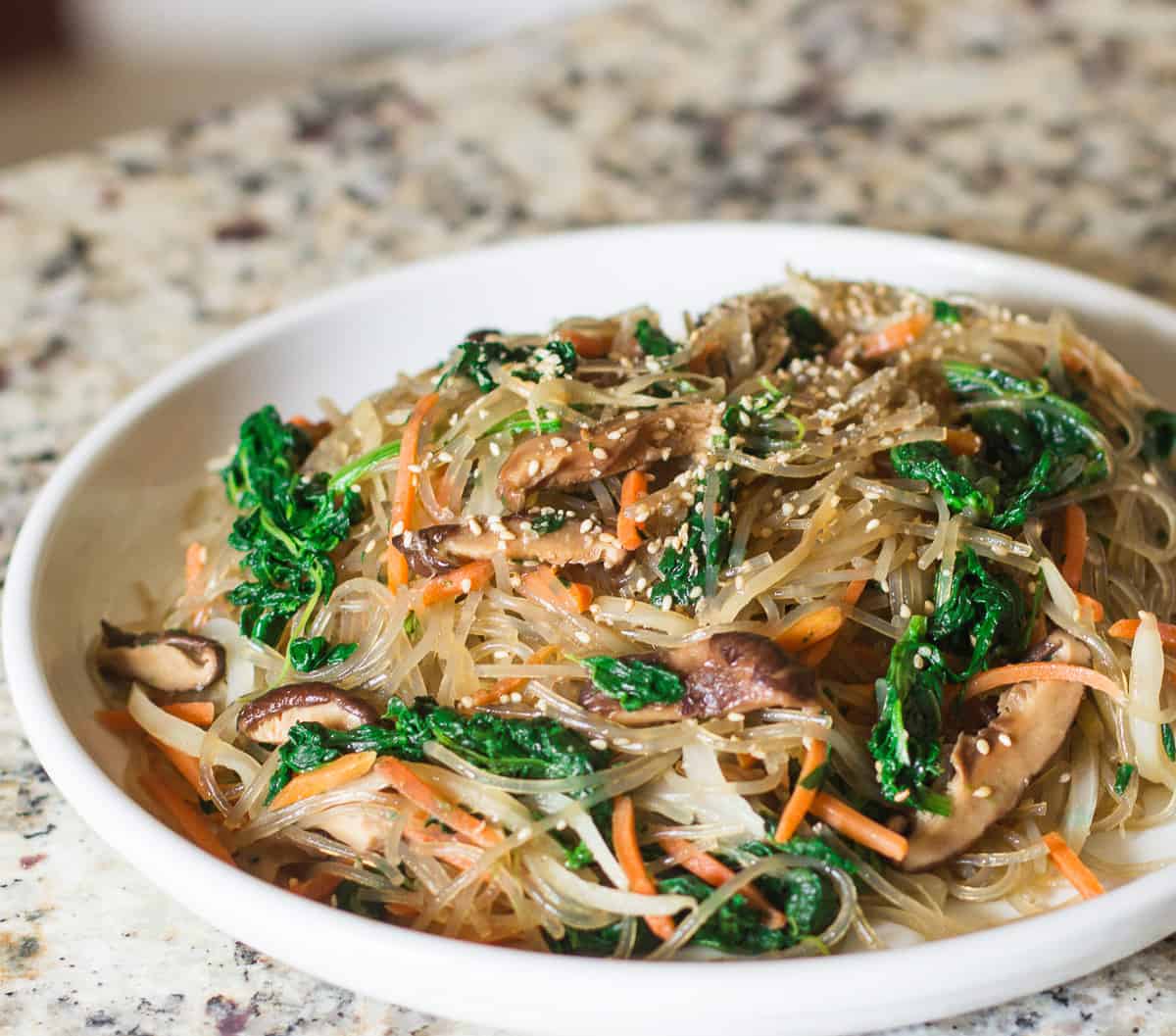 A side view of japchae in a large white plate.