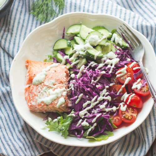 greek salmon salad with cabbage, tomatoes, and cucumber drizzled with tzatziki sauce