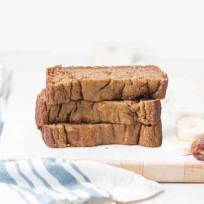 three slices of banana date bread stacked on a wooden board