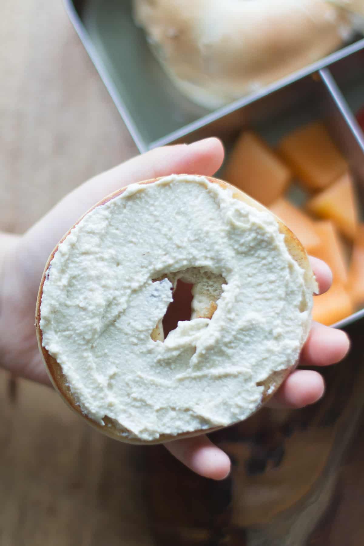 A close up shot of cream cheese spread on toasted bagel half.