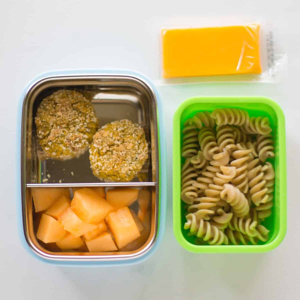 veggie nuggets with cantaloupe in bento box and cooked pasta with cheese in a small container.