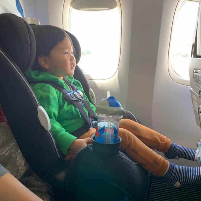 toddler sitting on a carseat on the airpane