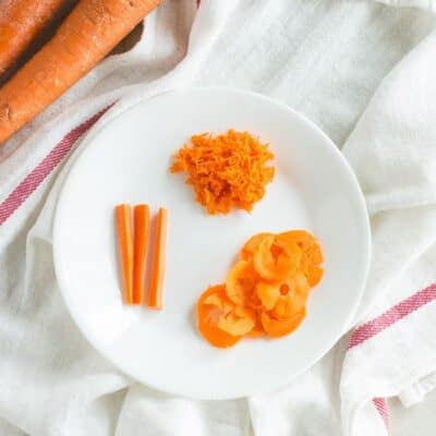 carrots served three ways shredded, thin strips, spiralized on a white plate