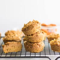 stacked pumpkin bean muffins and a sliced muffin next to it on a wire rack