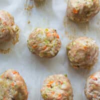Baked turkey meatballs on a parchment paper lined baking sheet.