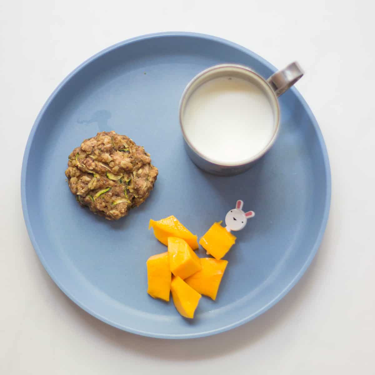 A cookie with mangoes and a glass of milk.