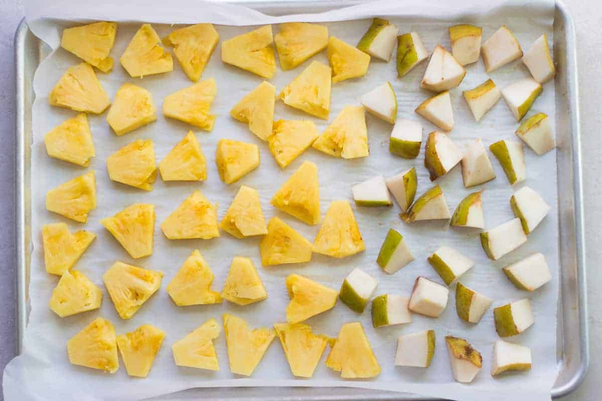 chopped pineapple and pears laid out in single layer on lined baking sheet