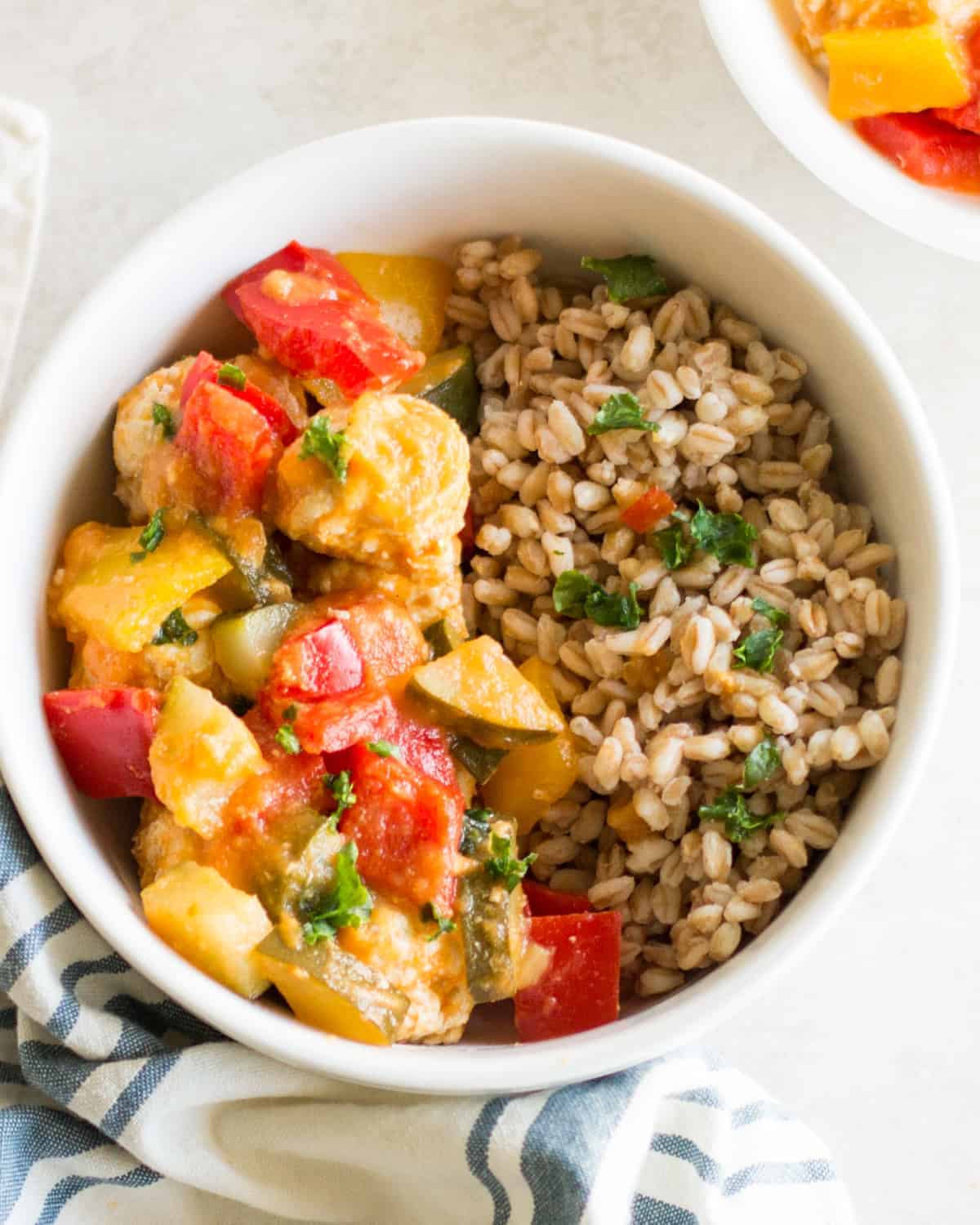 cooked sweet and sour meatballs with vegetables and farro in a white bowl