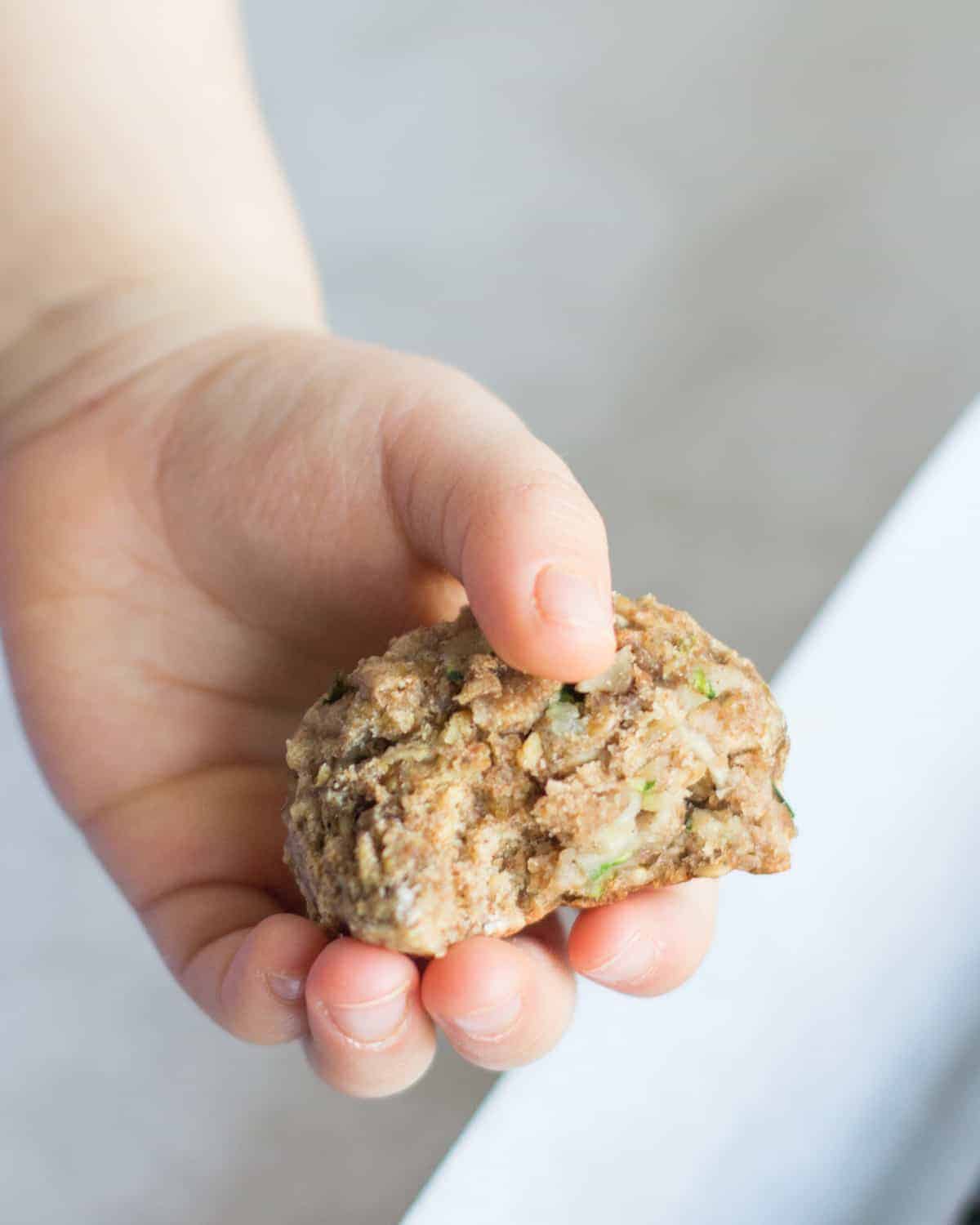 a toddler hand holding the zucchini bread cookie
