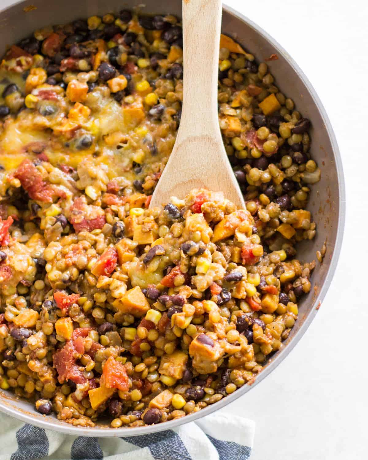A close up look at the Mexican lentils in a skillet with a large wooden spoon