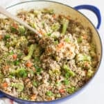 ground beef and broccoli quinoa in a large blue skillet with a small amount scooped onto an orange spatula