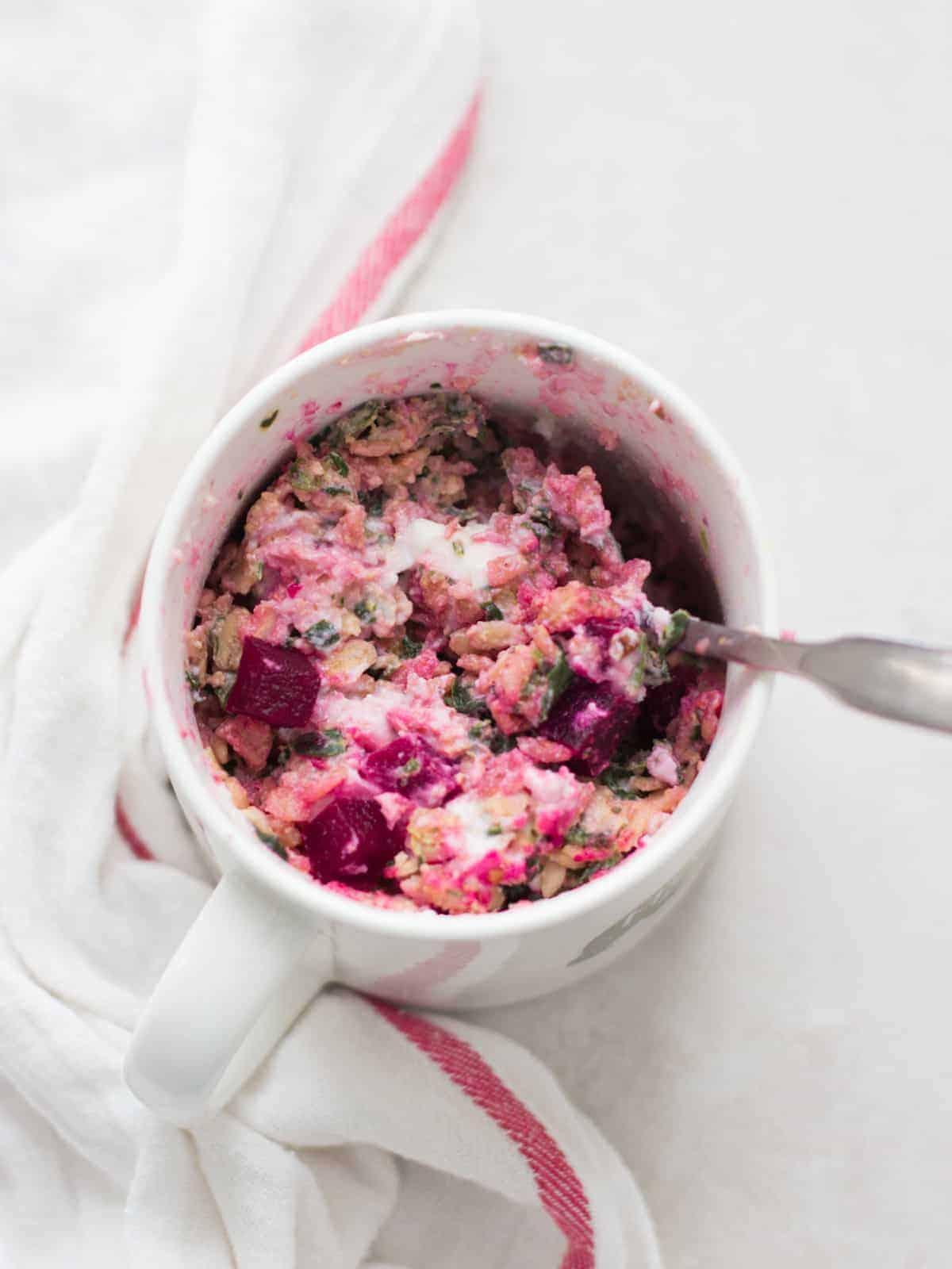 beetroot curry oatmeal served in a mug with a spoon