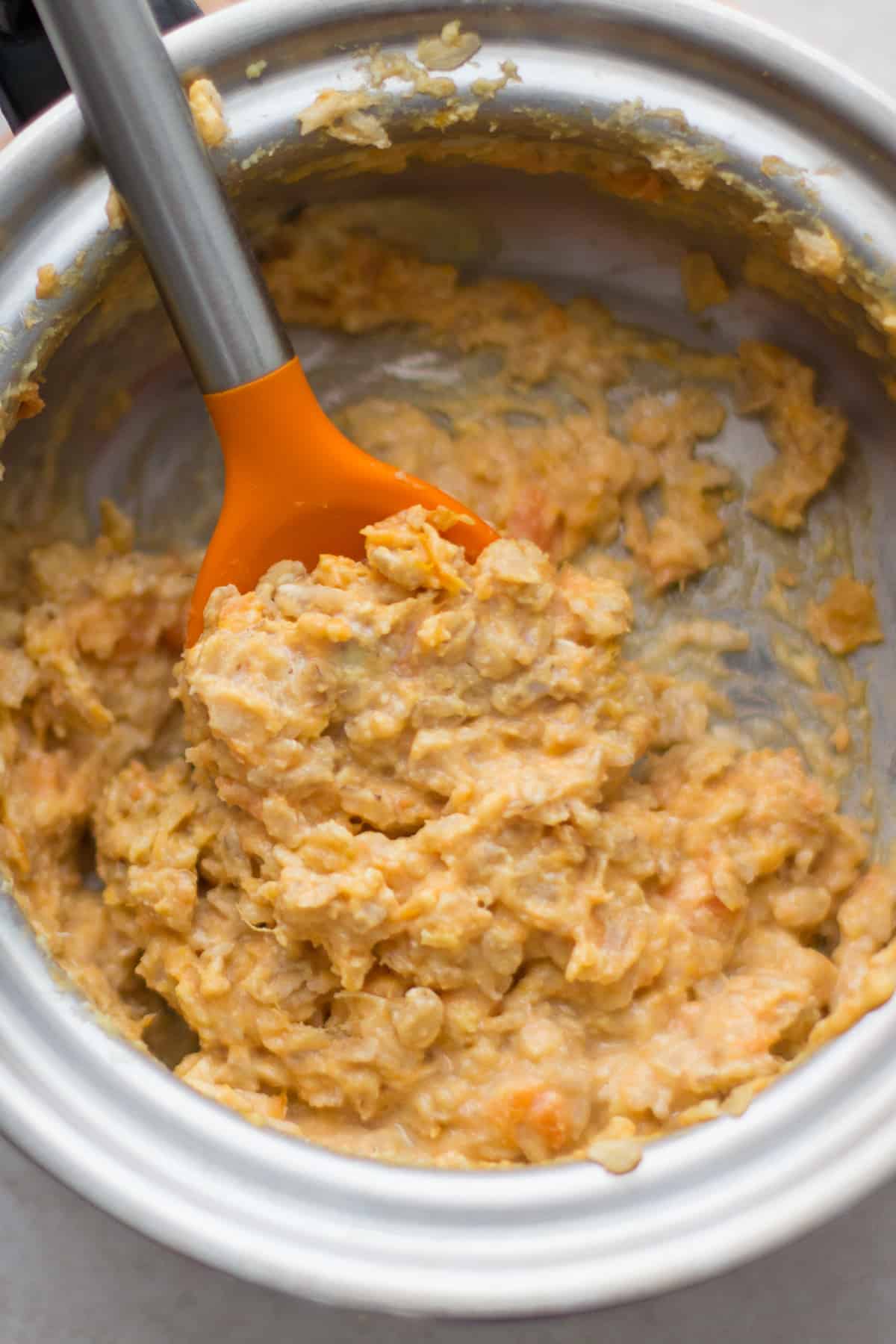 a close up shot of what sweet potato oatmeal looks like cooked on the stove.