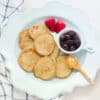 baby friendly banana protein pancakes spread out on a blue plate with berries and peanut butter