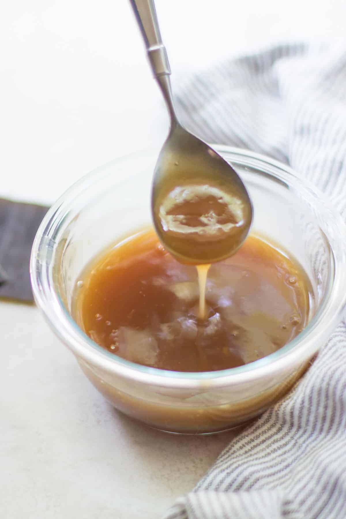 a close up shot of teriyaki sauce dripping from a spoon