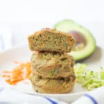 three stacked zucchini carrot avocado muffins with the very top one sliced in half to show the inside