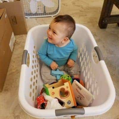 baby inside a laundry basket with toys