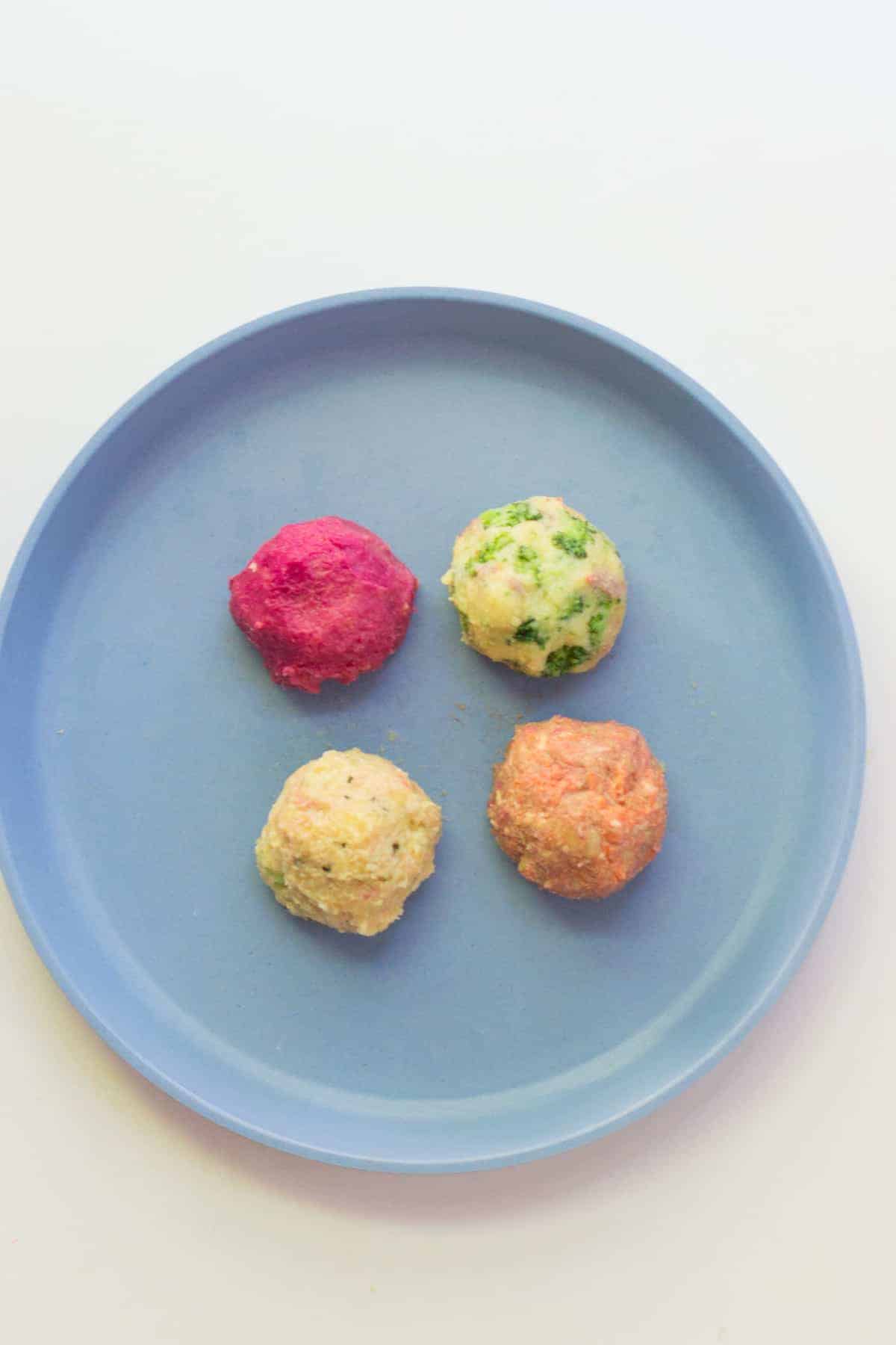 the four different variations of lentils shaped into balls and placed on a blue plate