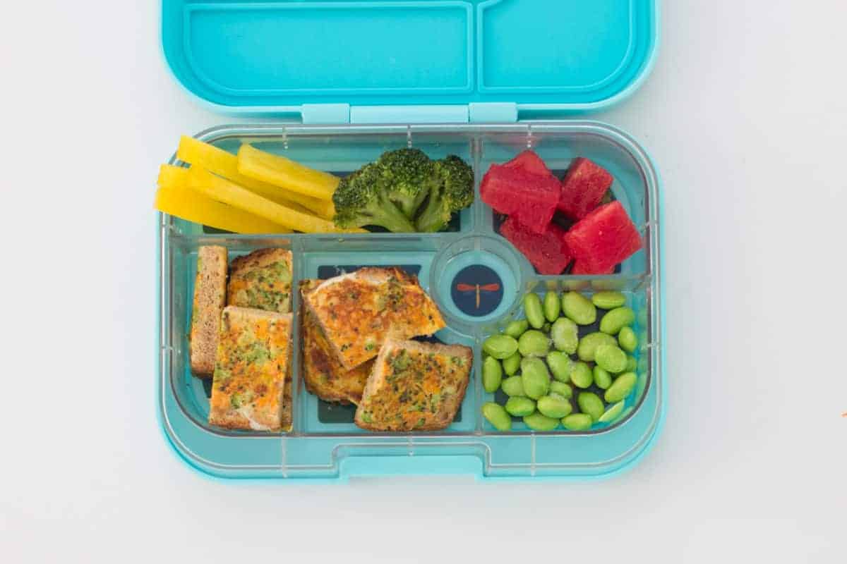 sliced vegetable French toast, frozen edamame, watermelon, broccoli, and yellow bell pepper strips in an aqua kid's lunchbox