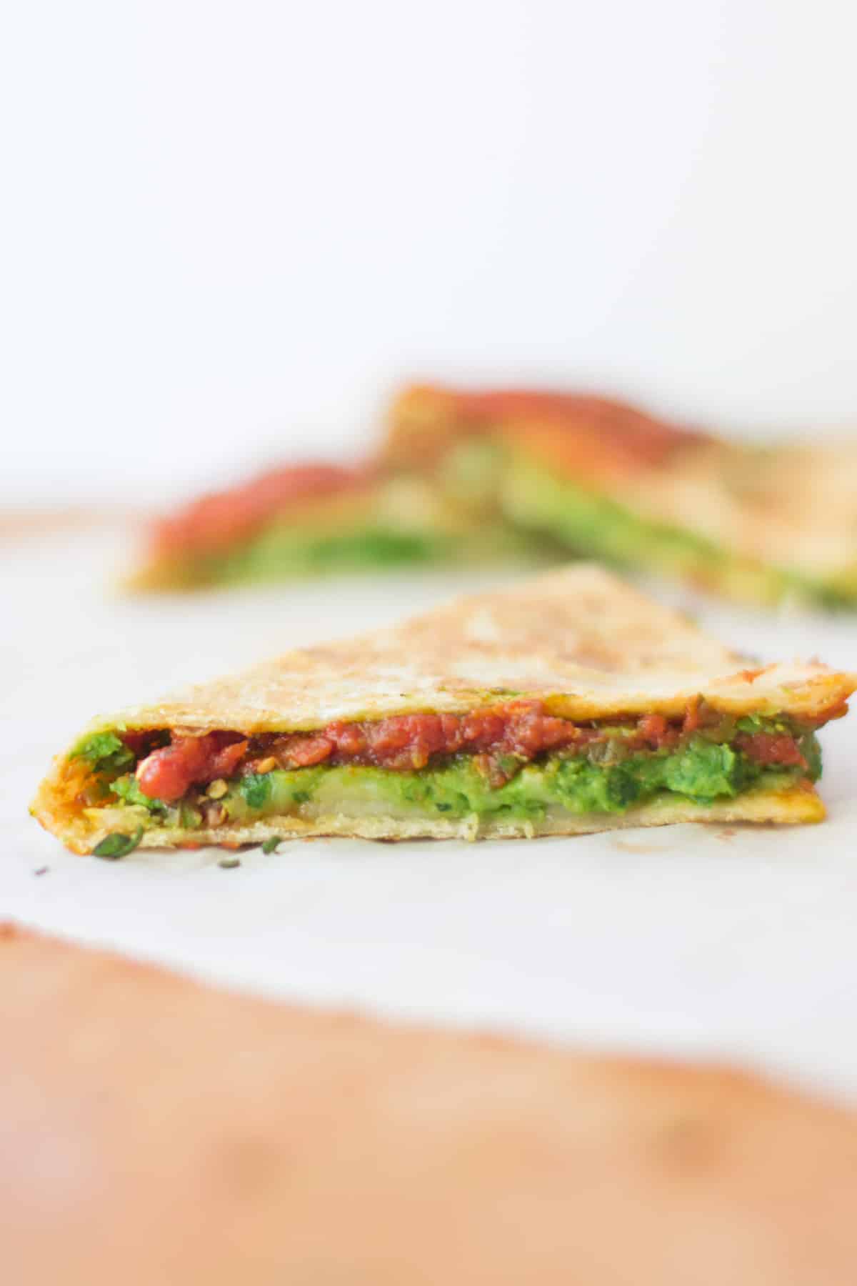 a close up shot of a cooked quesadilla triangle showcasing the filling