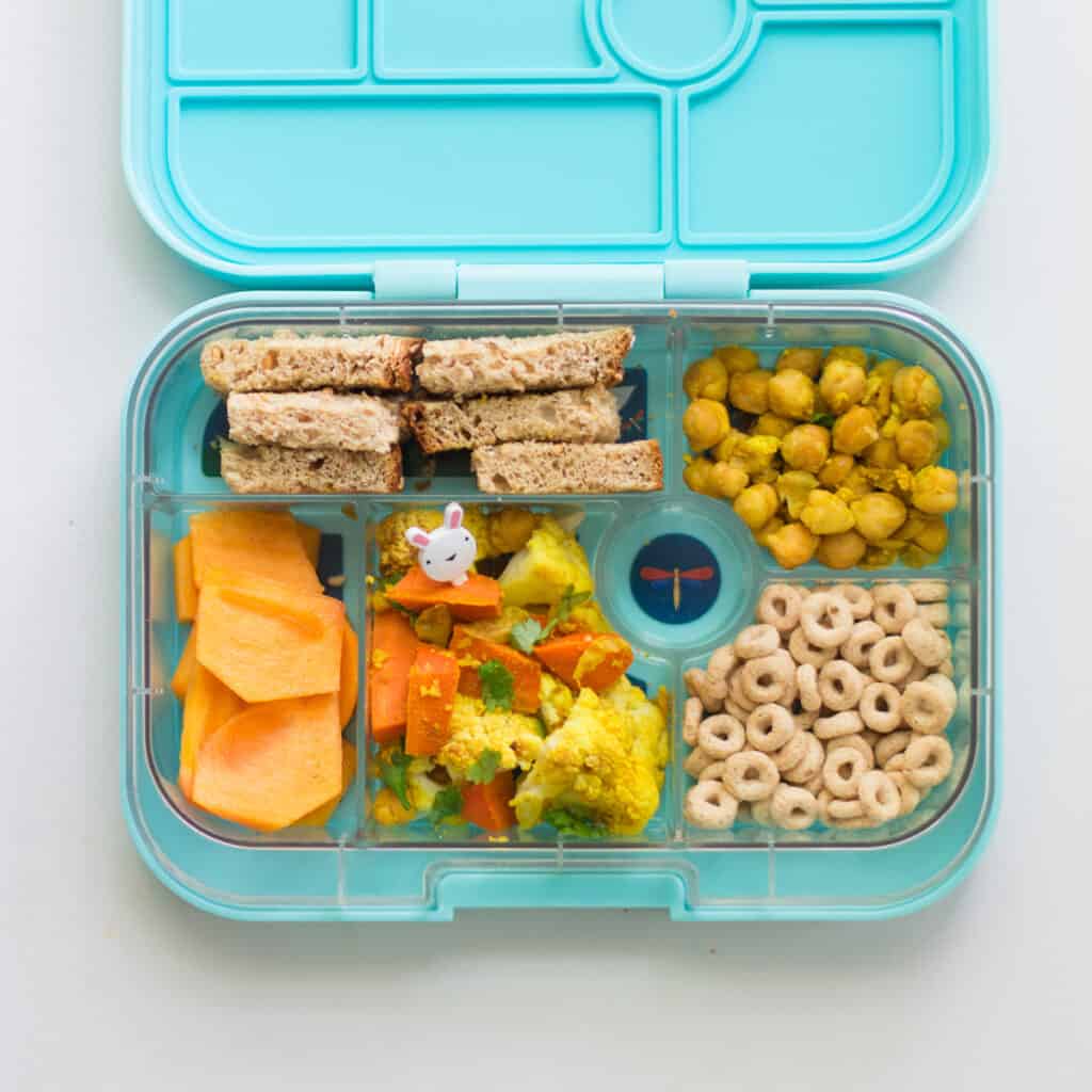 toddler's lunchbox including Indian roasted cauliflower, cheerios, persimmons, bread slices, and chickpeas