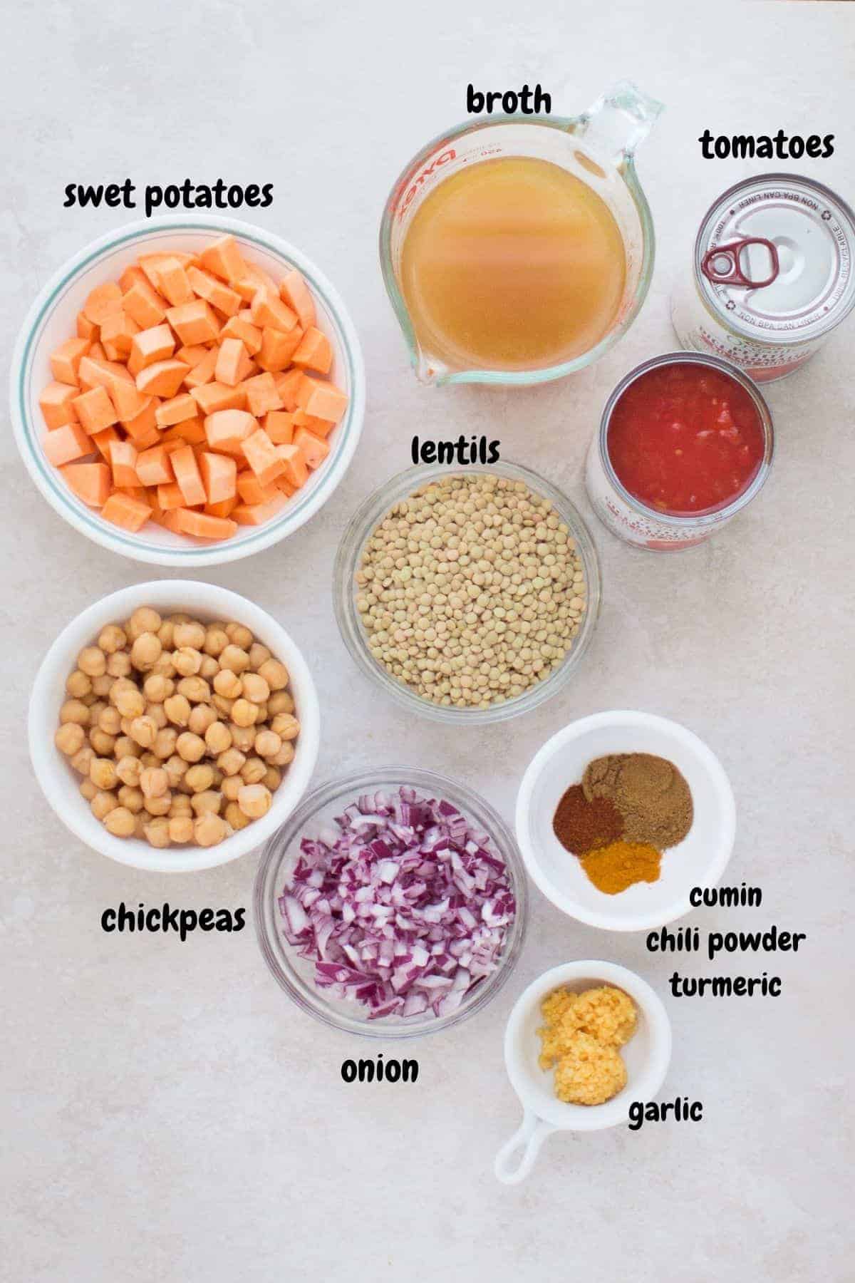 all the ingredients for lentil chili laid out on a white background