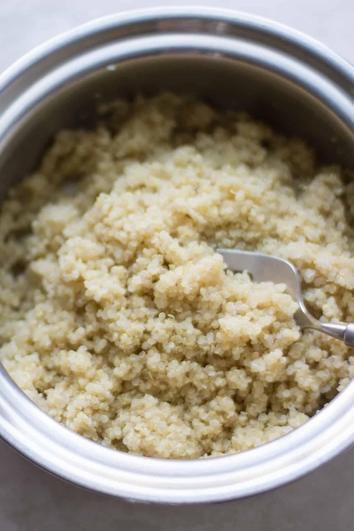 cooked quinoa in a pot with a large fork.