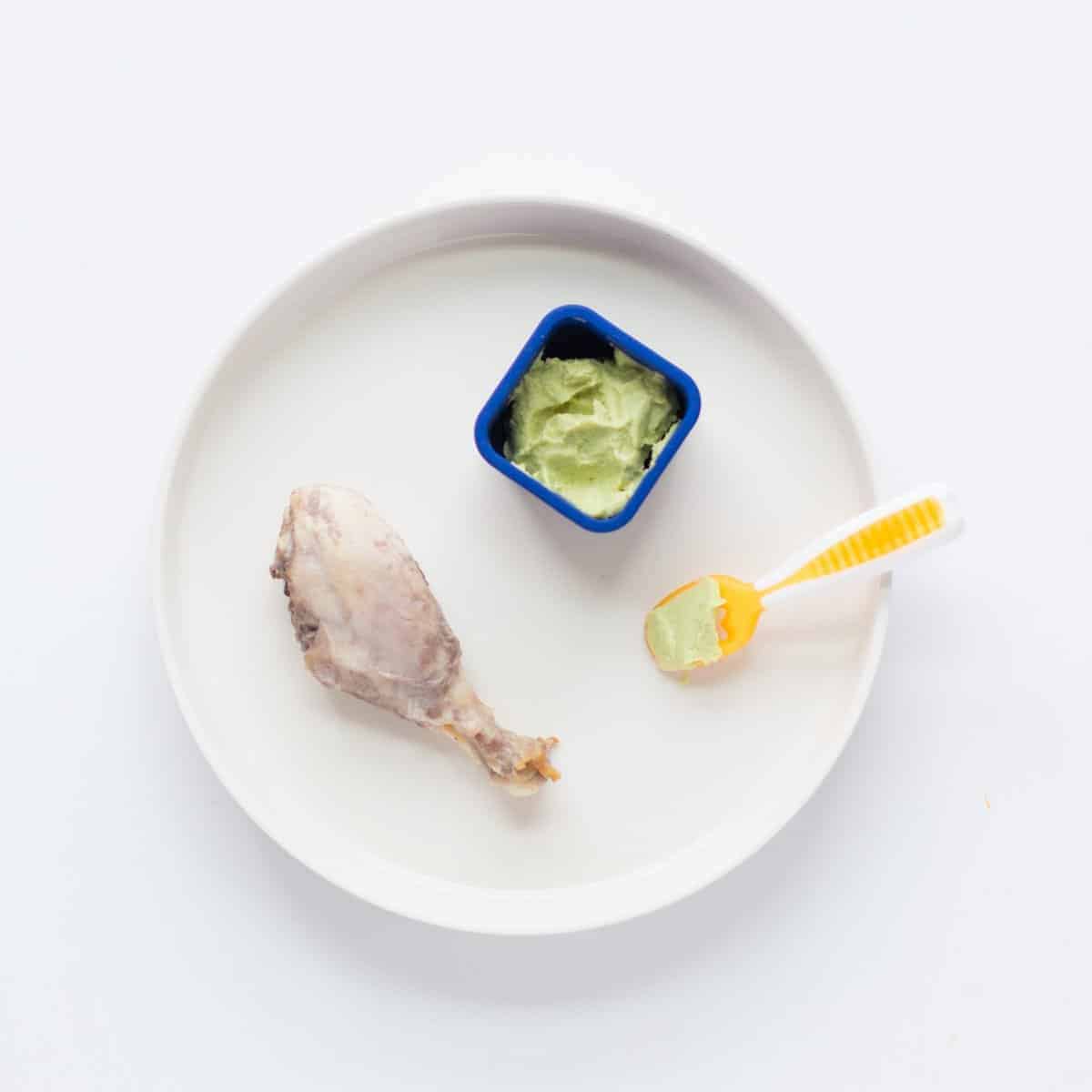 yogurt marinated drumstick with edamame guacamole on a white plate.