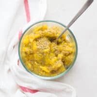 Mango chia seed jam in a glass bowl with a small spoon.