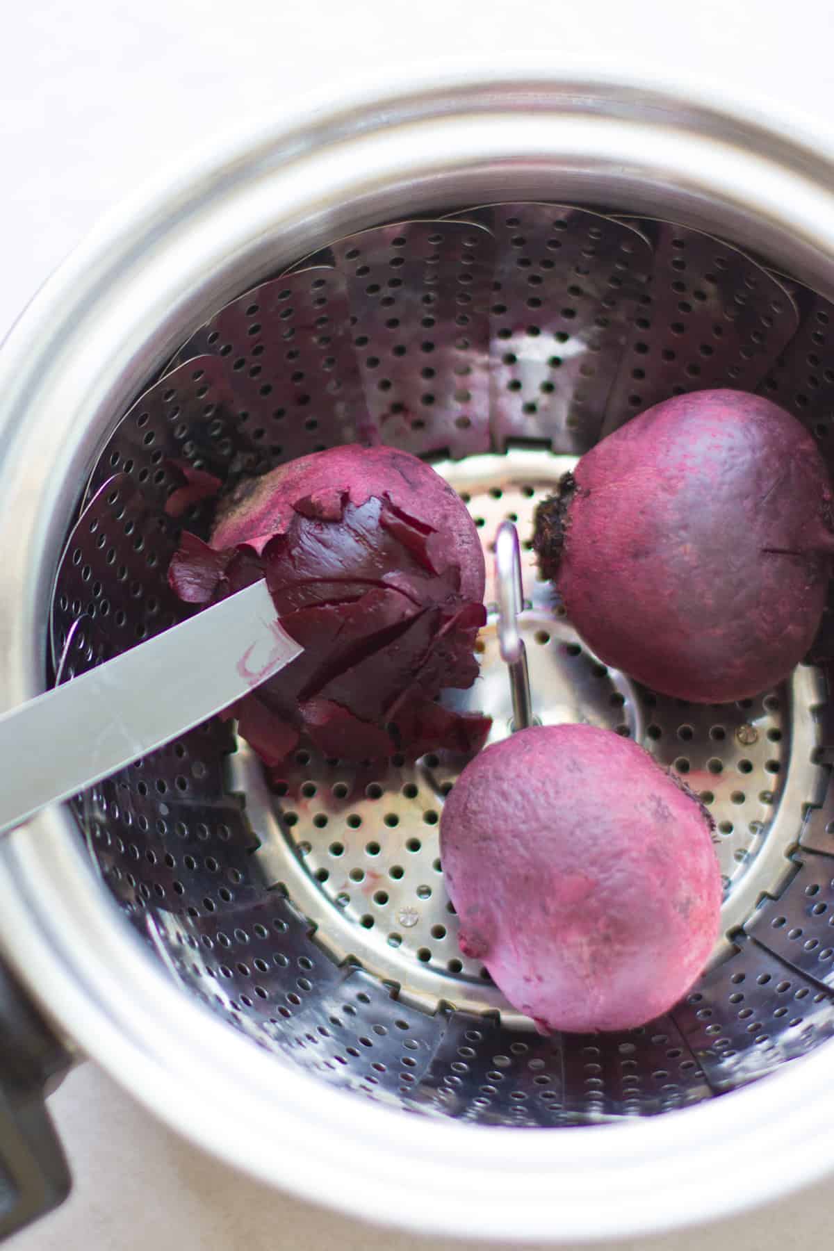 three beetroots cooked in a steamer basket.