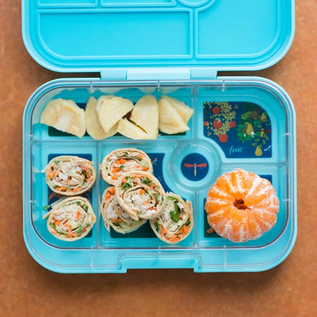 roll ups in a blue compartmentalized lunch box with parsnips and clementine.