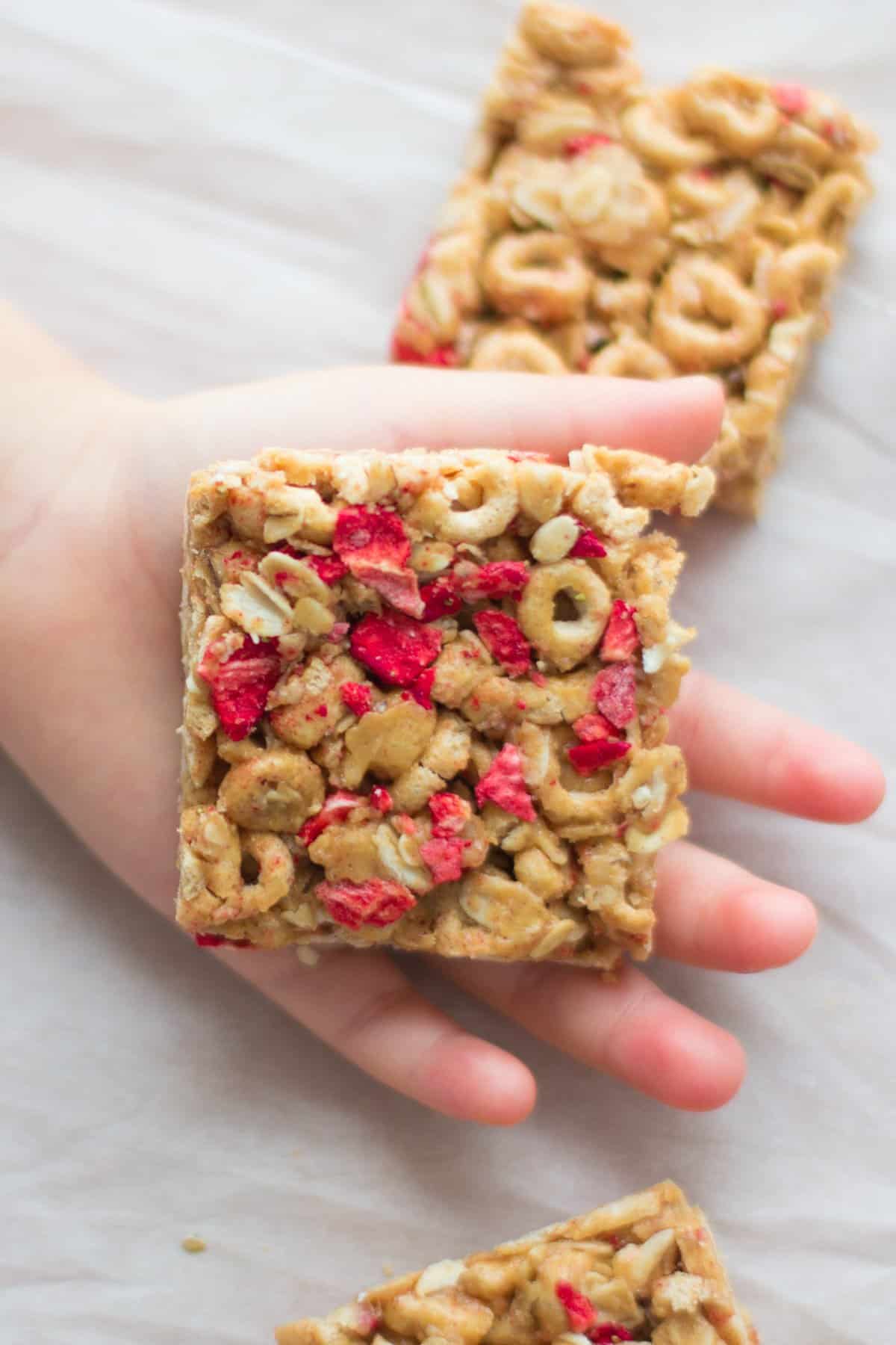 a square cereal bar placed on toddler's palm.