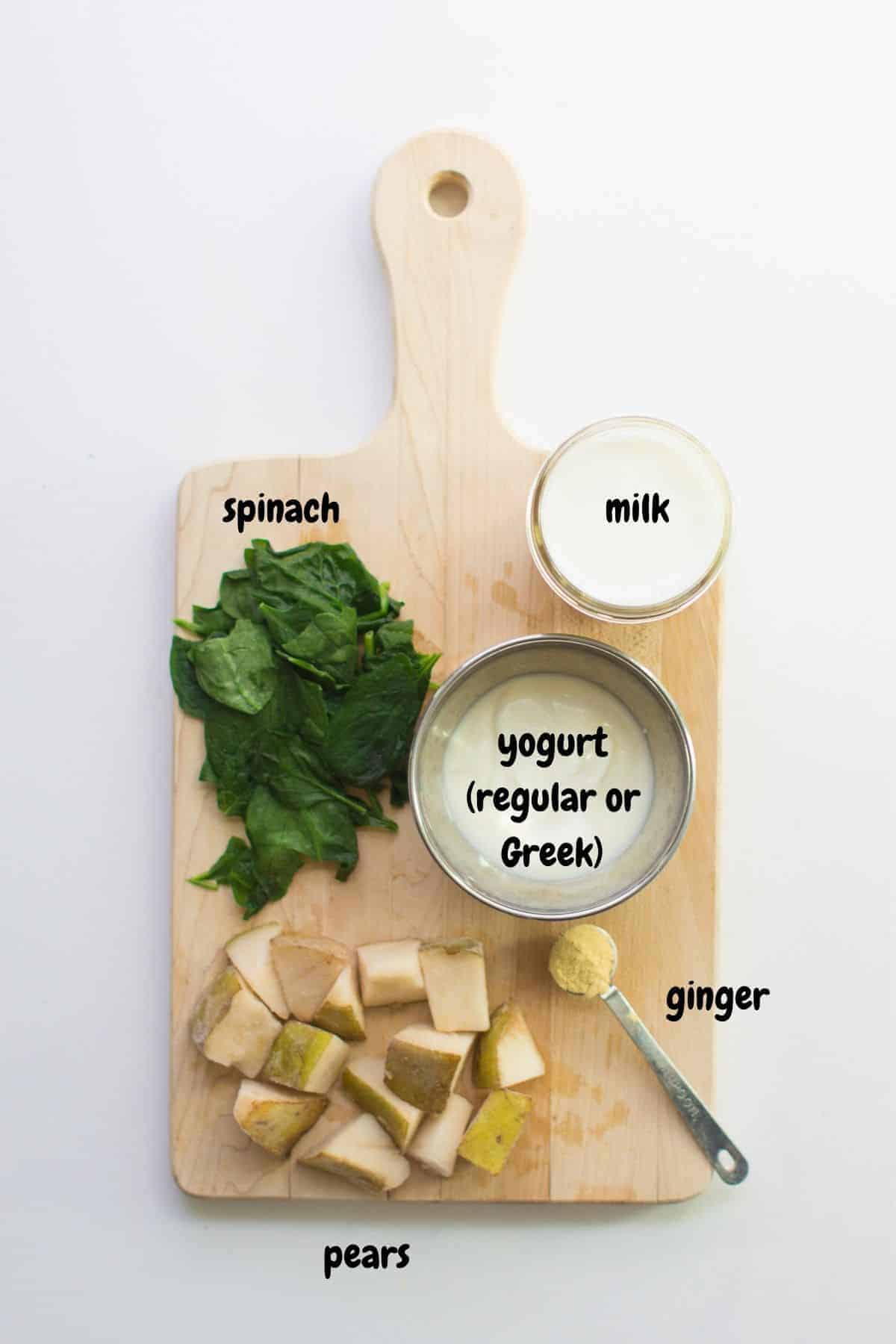 ingredients for pear ginger green smoothie laid out on a wooden board.
