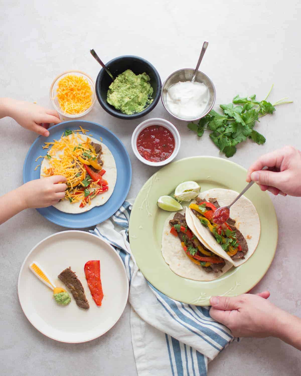 flank steak fajitas served family-style with an assortment of toppings and toddler, baby, and adult's plate with tortilla.