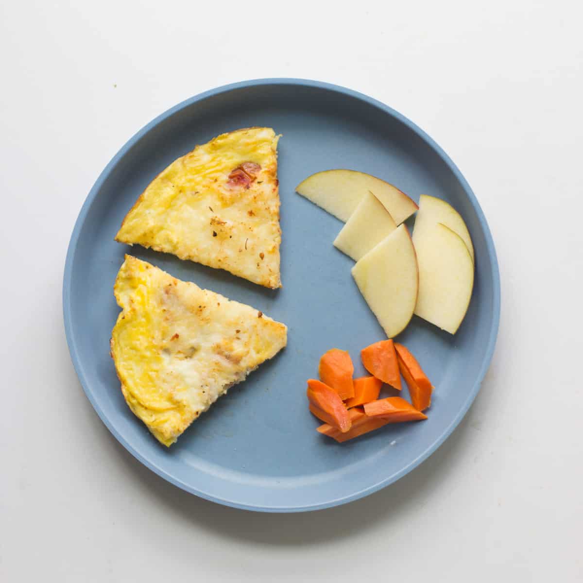 Two pizza egg slices with carrots and apples.
