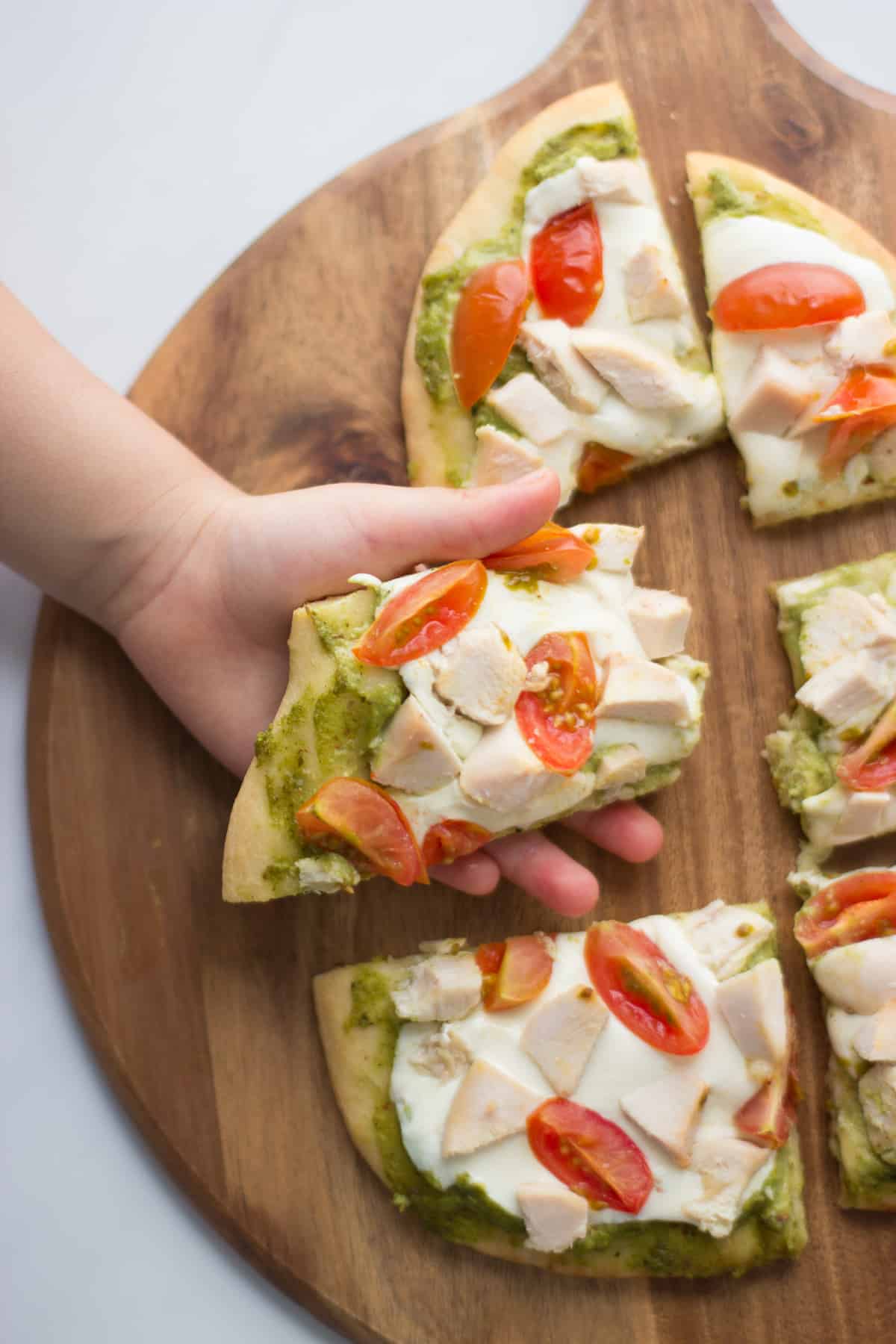 a toddler holding a slice of flatbread pizza.