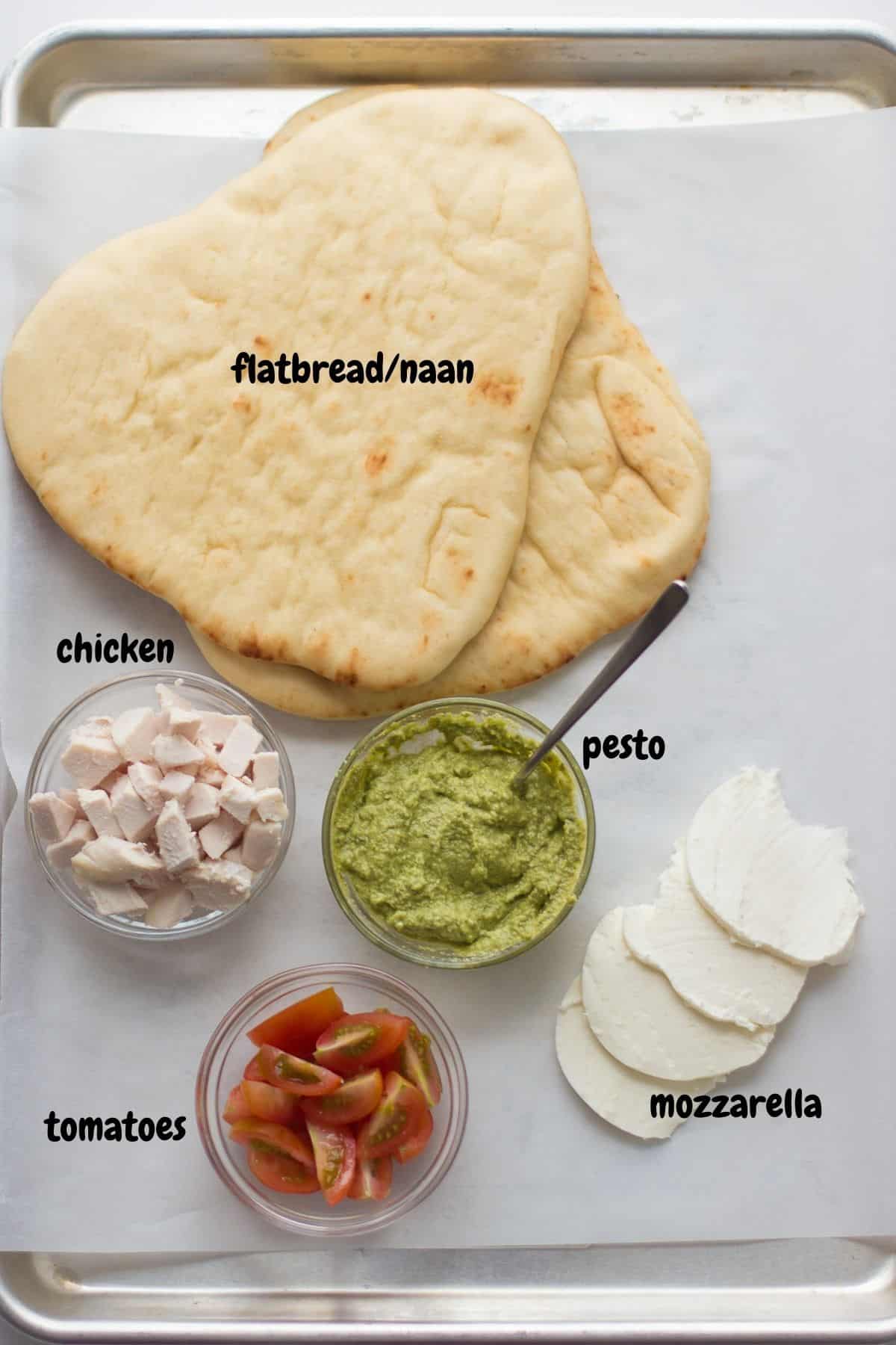 All the ingredients for flatbread pizza laid out on a white background.