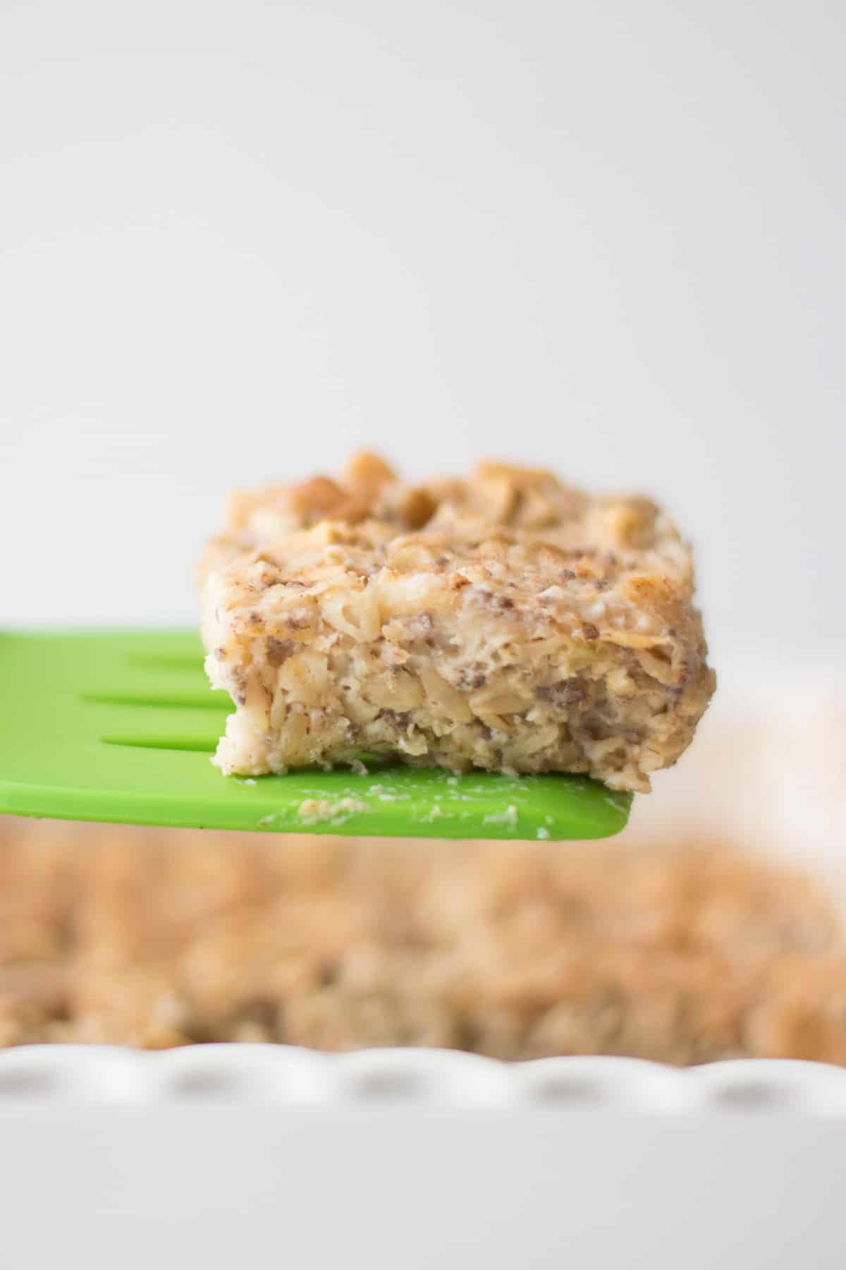 A slice of oatmeal lifted in the air by green spatula.