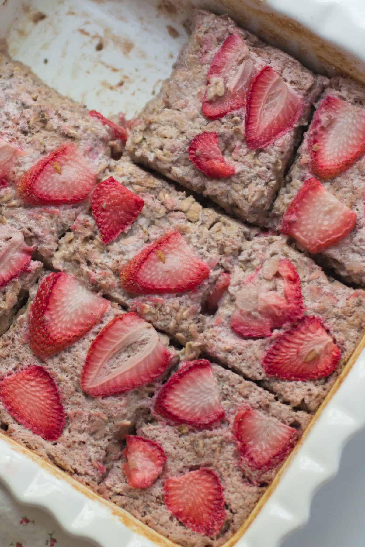 A close up shot of baked strawberry oatmeal in a pan.