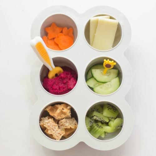 Carrots, beet hummus, cheese, cucumber, waffles, and broccoli in a muffin tray.