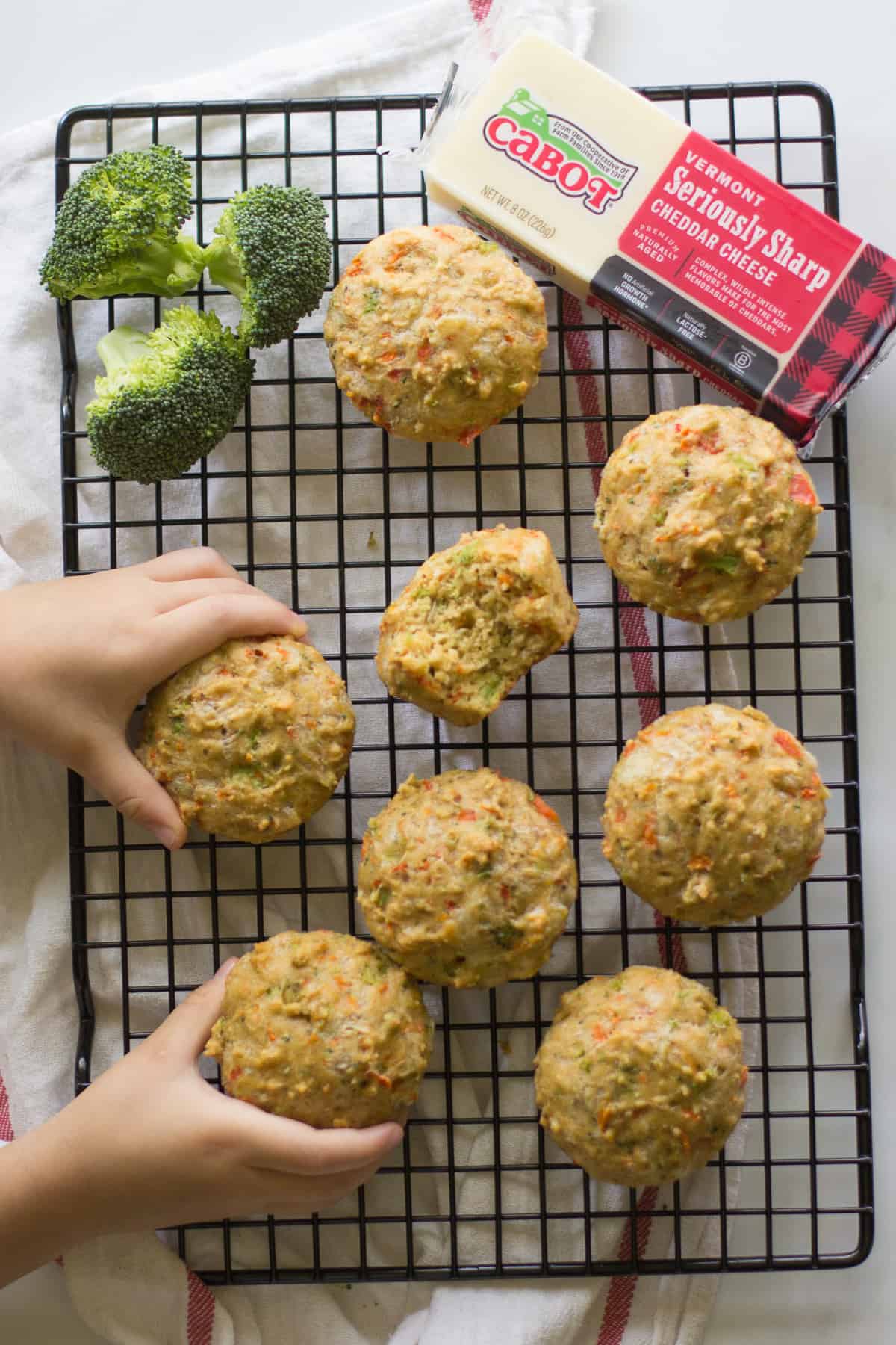 Vegetable muffins on a wire rack with cheese and broccoli.