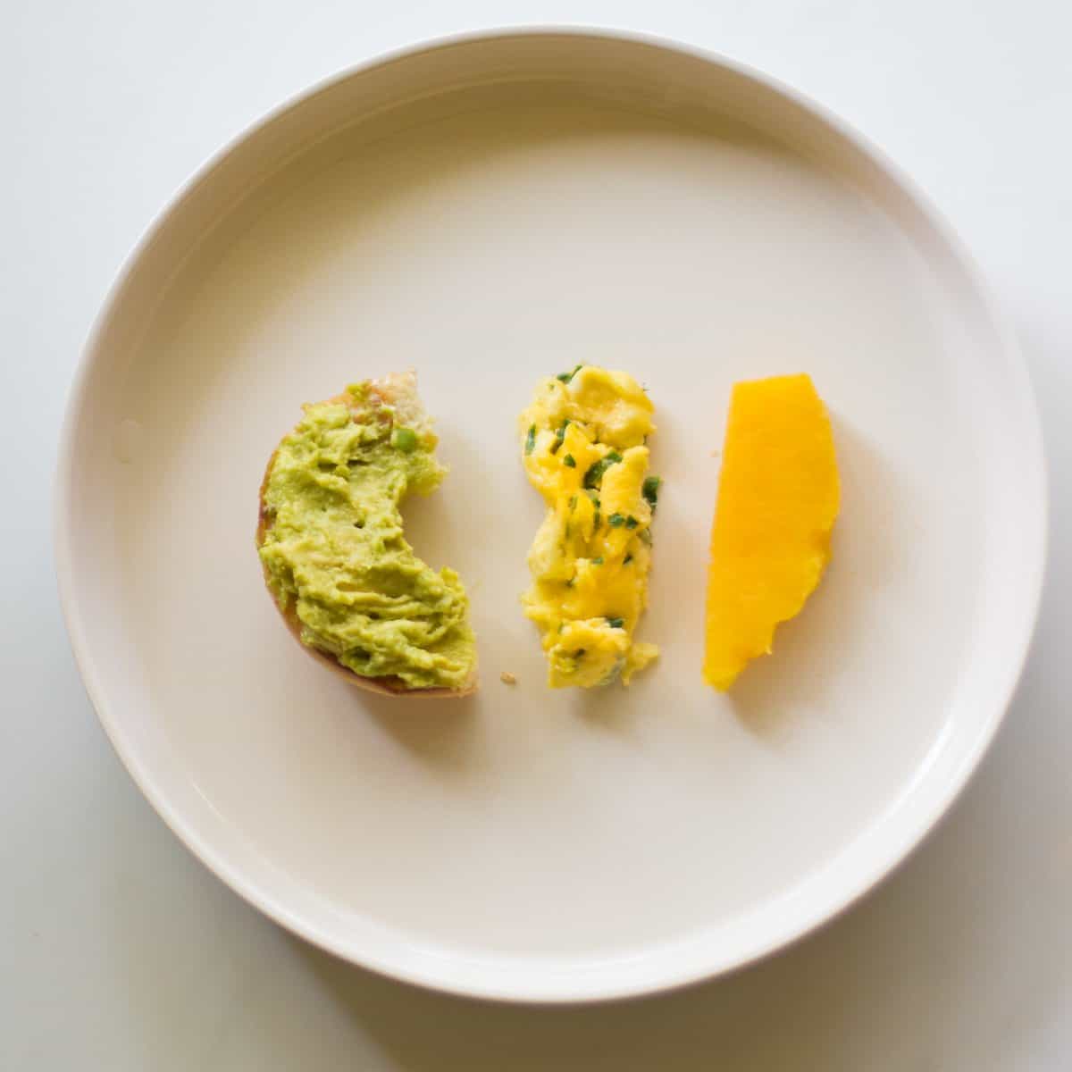 baby's plate with avocado bagel, scrambled eggs, and acorn squash.