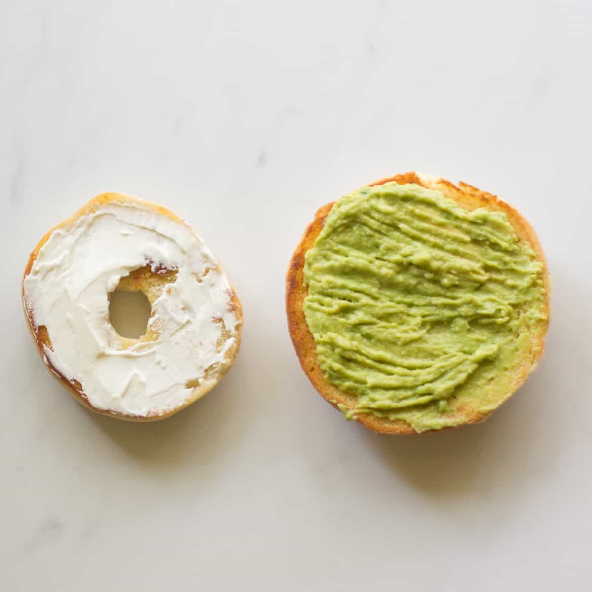 Mini bagel topped with cream cheese and brioche bun with mashed avocado.