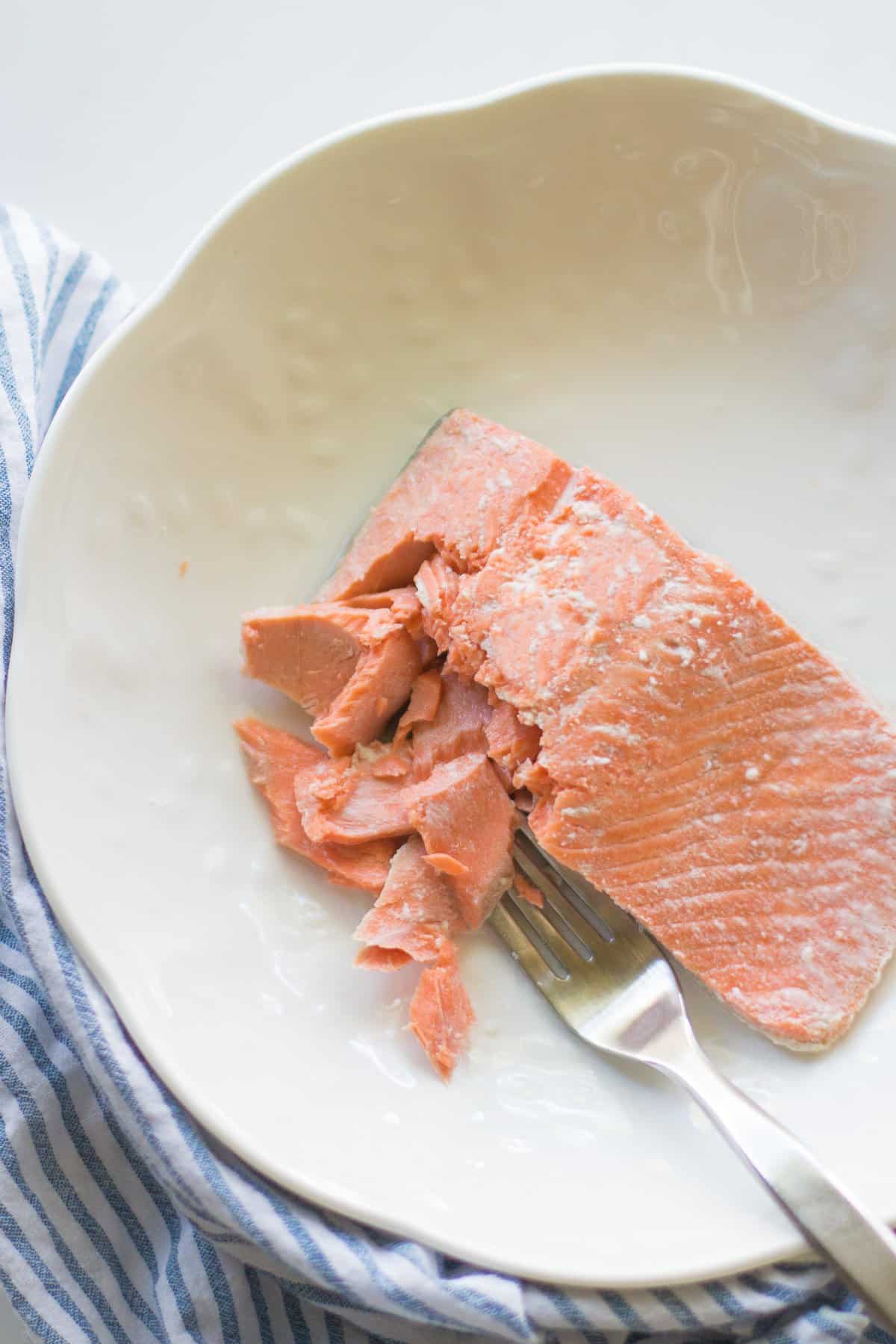 Poached salmon flaked with a fork.