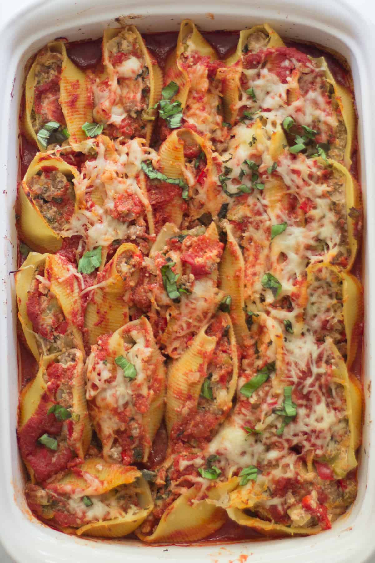 An overhead shot of baked pasta shells in a white baking dish.